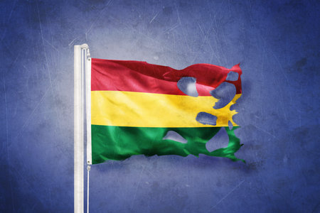 Torn flag of Bolivia flying against grunge backgroundの写真素材