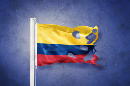 Torn flag of Colombia flying against grunge backgroundの写真素材