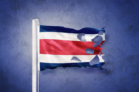 Torn flag of Costa Rica flying against grunge backgroundの写真素材
