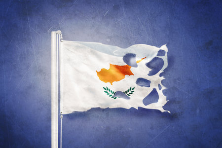 Torn flag of Cyprus flying against grunge backgroundの写真素材