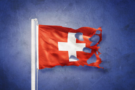 Torn flag of Switzerland flying against grunge backgroundの写真素材
