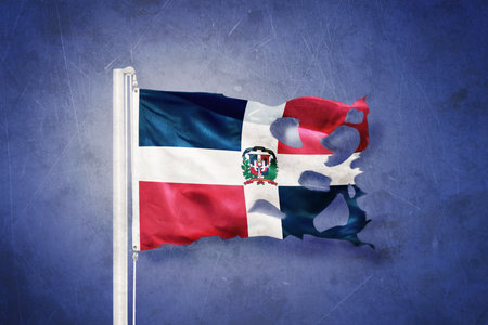 Torn flag of Dominican Republic flying against grunge backgroundの写真素材
