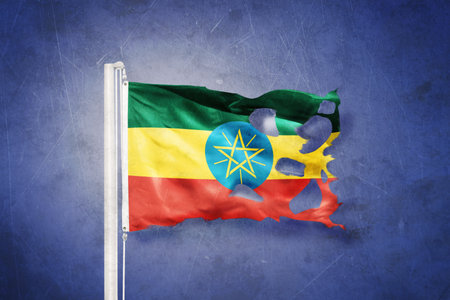 Torn flag of Ethiopia flying against grunge backgroundの写真素材