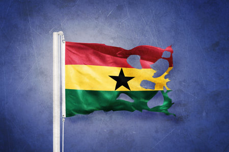 Torn flag of Ghana flying against grunge backgroundの写真素材