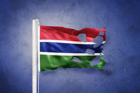 Torn flag of Gambia flying against grunge backgroundの写真素材