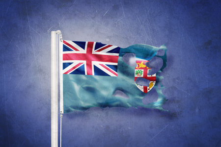 Torn flag of Fiji flying against grunge backgroundの写真素材
