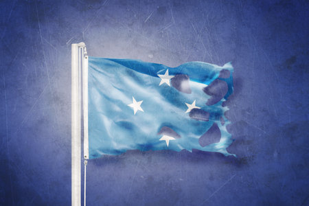Torn flag Federated States of Micronesia flying against grunge backgroundの写真素材