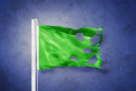 Torn green flag flying against grunge backgroundの写真素材