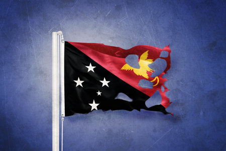 Torn flag of Papua New Guinea flying against grunge backgroundの写真素材