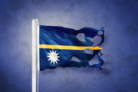Torn flag of Nauru flying against grunge backgroundの写真素材