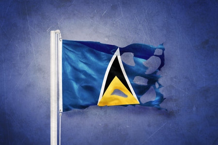Torn flag of Saint Lucia flying against grunge background