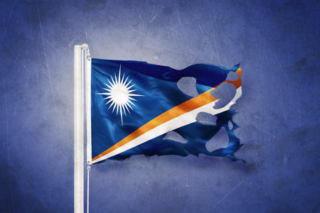 Torn flag of Marshall Islands flying against grunge backgroundの写真素材