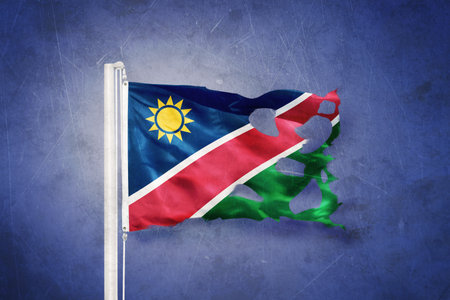 Torn flag of Namibia flying against grunge backgroundの写真素材