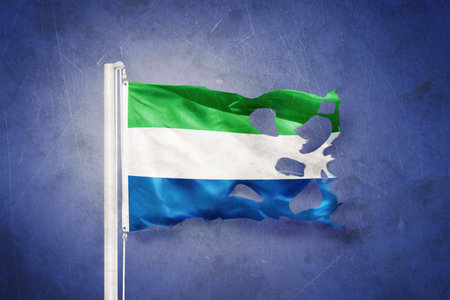 Torn flag of Sierra Leone flying against grunge backgroundの写真素材