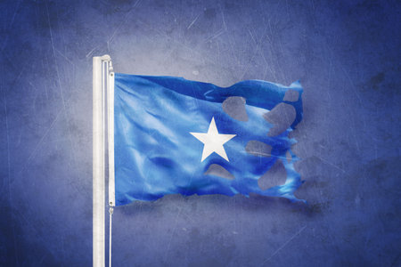 Torn flag of Somalia flying against grunge backgroundの写真素材