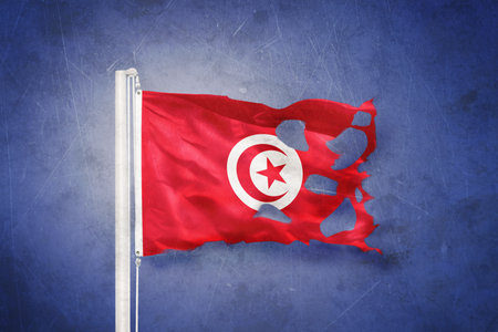 Torn flag of Tunisia flying against grunge backgroundの写真素材