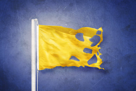 Torn Yellow flag flying against grunge backgroundの写真素材