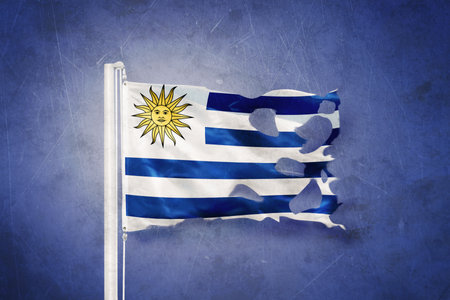 Torn flag of Uruguay flying against grunge backgroundの写真素材