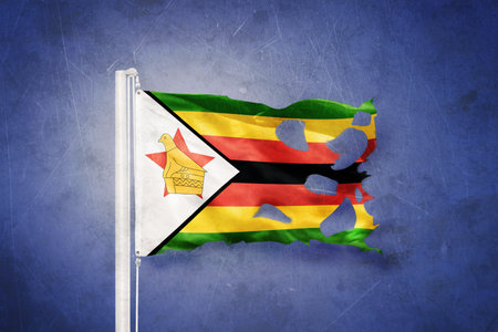 Torn flag of Zimbabwe flying against grunge backgroundの写真素材