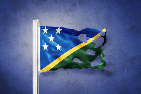 Torn flag of Solomon Islands flying against grunge backgroundの写真素材