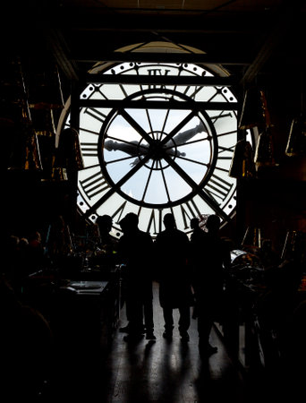 inside orsay museum and there is a big clock two people stand beside the clock