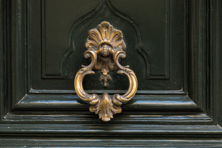 Old metal door handle knocker on a wooden background