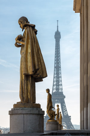 Paris, France, March 27 2017: Golden bronze statues in the Trocadero garden, Eiffel tower in the backgroundのeditorial素材