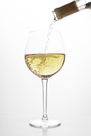 pouring white wine into glass, on white backgroundの写真素材