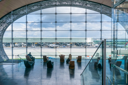 Paris, France, April 1, 2017: Looking out a large ellipsoid window at Charles De Gaulle airport with two rows of chairs in silhouette in front of itのeditorial素材