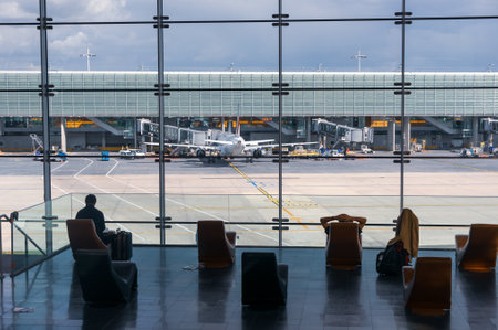 Paris, France, April 1, 2017: Looking out a large ellipsoid window at Charles De Gaulle airport with two rows of chairs in silhouette in front of itのeditorial素材