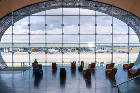 Paris, France, April 1, 2017: Looking out a large ellipsoid window at Charles De Gaulle airport with two rows of chairs in silhouette in front of itのeditorial素材