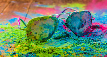Holi color powder on sunglasses. Organic Gulal colours on eyeglasses for Holi festival, Hindu...
