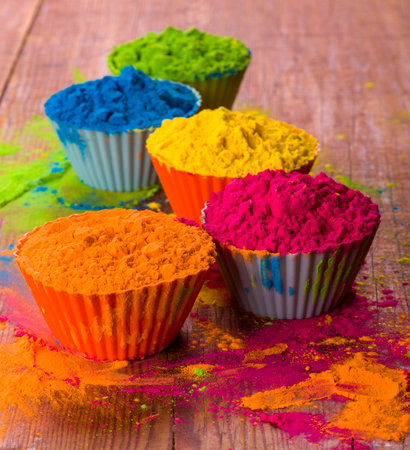 Holi color powder. Organic Gulal colours in bowl for Holi festival, Hindu tradition festive. Blue, pink, magenta, orange, yellow holi dry paints on wood desk background.の写真素材