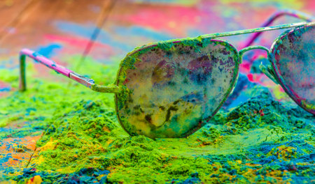 Holi color powder on sunglasses. Organic Gulal colours on eyeglasses for Holi festival, Hindu...
