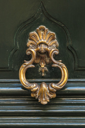 Detail of a bronze metal knocker on a wooden door of house