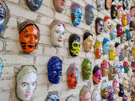 Moscow, Russia, 21 October 2019: Colorful painted ceramic faces sculpture on the bricks wall as an the object of modern art. Hundred faces by Marat Nabi. Bricks wall with decorative elementのeditorial素材