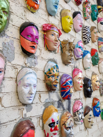 Moscow, Russia, 21 October 2019: Colorful painted ceramic faces sculpture on the bricks wall as an the object of modern art. Hundred faces by Marat Nabi. Bricks wall with decorative elementのeditorial素材