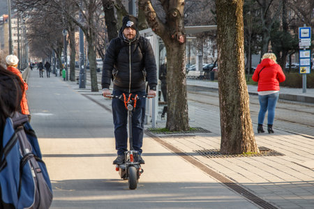 Budapest, Hungary, March 22 2018: Young man rides an electric scooter at high speed, without helmet nor protection. Nowadays, electric scooter and skateboard have taken over the world by stormのeditorial素材
