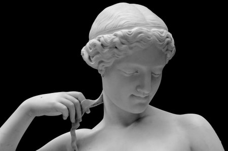 White marble sculpture head of young woman. Statue of sensual renaissance art era naked woman in circlet antique style isolated on black backgroundの写真素材