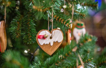 Christmas tree branch with wooden decorative toys and gingerbread homemade sweet cookie on dark...