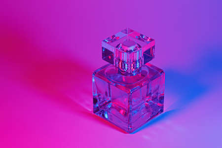 Perfume bottle with on neon light background. Blank perfumery mockup, spa branding concept.Glamour fragrance, eau de parfum.の写真素材