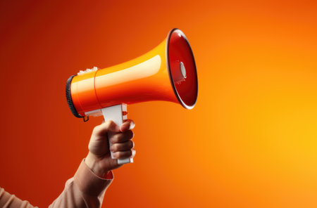 Megaphone in hand on a orange background, attention concept announcement.の素材