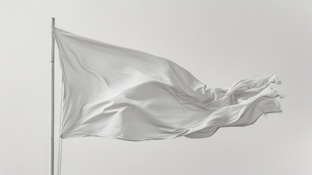 White flag fluttering against blue sky on sunny day.の素材