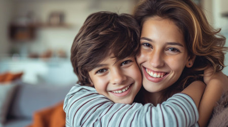 Portrait of beautiful young mother cuddling with teen son at home.の素材