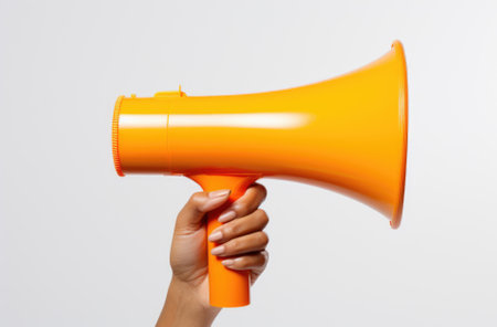 Close up of female hand holding orange megaphone against white backgroundの素材