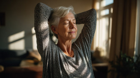 Senior woman practicing yoga stretching exercise at home with eyes closed, representing wellness, mindfulness, and healthy aging lifestyle.の素材