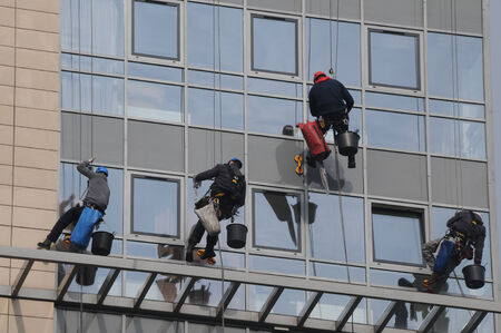 Maintenance workers climbing outside a skyscraper and clean
