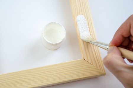 Woman hand painting picture frame on white color