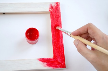 Woman hand painting picture frame on red colorの写真素材