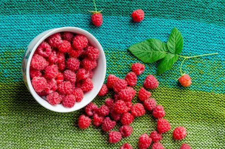 plate bent and ripe raspberries crumbled on linen green shades cloth